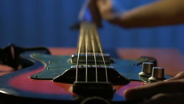 Guitarist looks at his bass guitar and wipe strings with piece of cloth