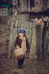 A little boy in an old fur coat and fur hat with a basket