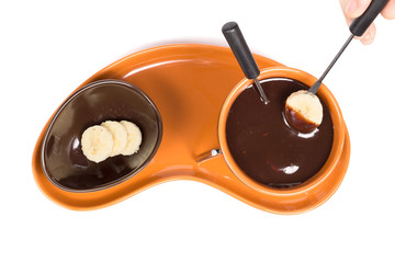 Chocolate fondue with sliced banana isolated on white