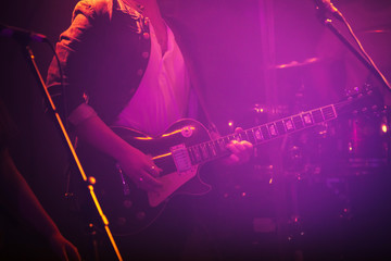 Electric guitar player in purple light - Powered by Adobe