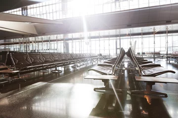 Papier Peint photo autocollant Aéroport modern airport terminal with black leather seats at sunset.