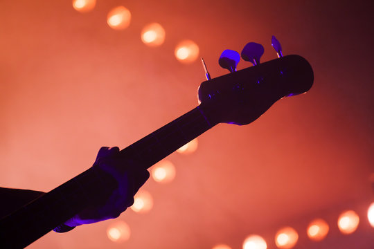 Bass guitar over bright blurred stage lights - Powered by Adobe