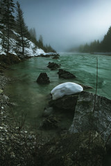  The river isar with turquoise water in winter on a foggy winter day at the sylvensteinspeicher