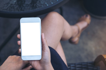 Top view mockup image of a woman sitting crossed leg and holding white mobile phone with blank desktop screen