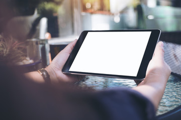 Mockup image of hands holding black tablet pc with blank white desktop screen and coffee cup on...