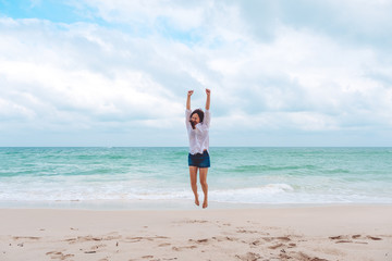 A woman jumping on the beach in front of the sea with feeling happy and freedom