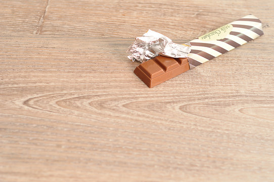 A Candy Bar Unwrapped Still In A Wrapper On A Wooden Background