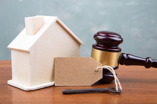 Real estate sale auction concept - gavel and house model on the wooden table