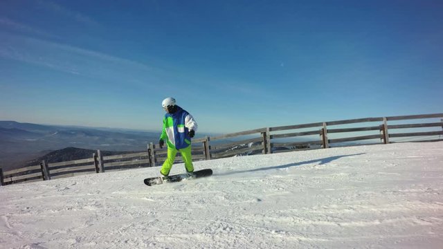 Snowboarder is riding down the top of a mountain in sunny winter day