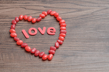 A heart shape made out of red jelly beans and the word love