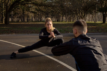 couple of young athlets do exercises outdoors in autumn park 