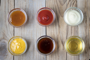a variety of sauces in glass bowls on a wooden table