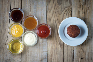 Obraz na płótnie Canvas a variety of sauces in glass bowls and a plate with a cutlet on a wooden table