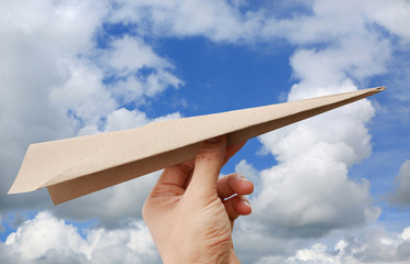 Aircraft rocket paper in hand on cloud sky background.
