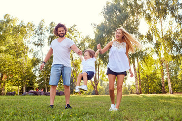 Fototapeta premium Happy family in the park. Parents with a child play in nature.
