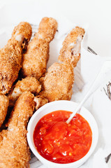 Traditional spicy fried or oven-baked chicken drumsticks or thights served with hot chili sriracha barbecue ketchup dipping sauce on game Sunday for Football Super Bowl party with family and friends