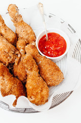 Traditional spicy fried or oven-baked chicken drumsticks or thights served with hot chili sriracha barbecue ketchup dipping sauce on game Sunday for Football Super Bowl party with family and friends