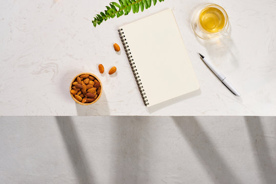 Minimal styled flat lay table with open notebook, croissant and tea.