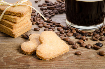 The cup of coffee, coffee beans and cookies-hearts related together on  wooden table