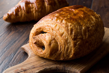 Freshly Baked Chocolate Croissant on Wooden Surface.