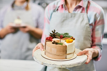 Confectioner holding tray with Christmas cake decorated with currant