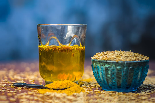 Cumin,Cuminum cyminum with its powder and its extracted water on brown wooden surface.