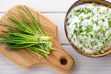Bowl of cream cheese with green onions, dip sauce on wooden table.