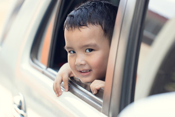 View from window, Portrait cute boy sitting in the car and look straight ahead at camera. He has...