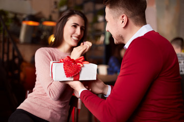 Beautiful couple in love celebrate Valentine's day in café and sharing gifts.