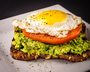 Avocado Toast with Sliced tomator and sunny side up fried egg.