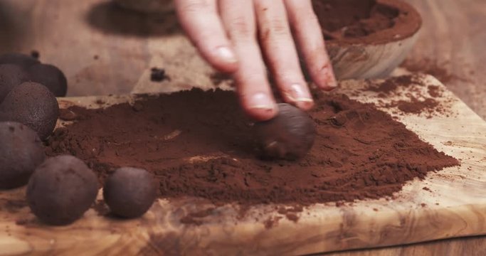 Slow motion handheld shot put truffles in cocoa powder on board