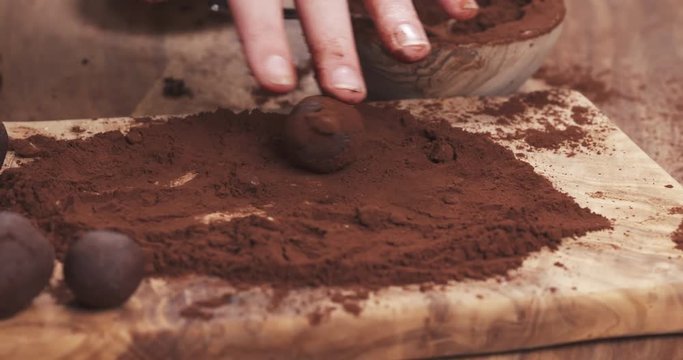 Slow motion handheld shot put truffles in cocoa powder on board