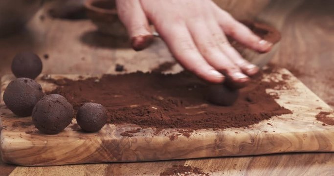 Slow motion handheld shot put truffles in cocoa powder on board