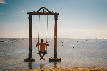 Mann sitzt auf einer Schaukel im Meer
