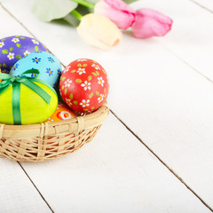 Rustic style painted easter eggs in basket on white table