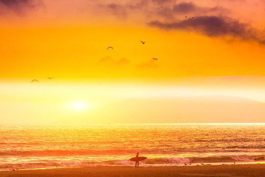 Silhouette, of Surfer walking on the beach at sunset. San Simeon beach, southern California © bluebeat76