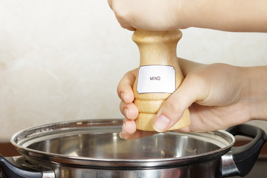 Female Hands Add To The Pot The Seasoning,on Which Is Written The Word Mind