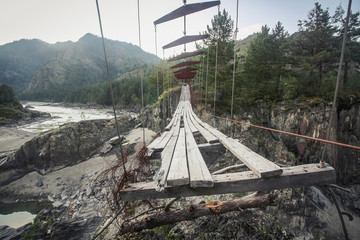 Abandoned suspended pedestrian bridge in mountains