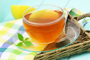 Lemon tea in transparent cup on wicker tray
