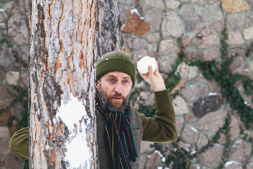 man with beard in his waistcoat throws snowballs between trees