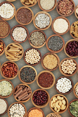Vegan dried health food with nuts, seeds, legumes, pasta, grains and cereals. Food high in fibre, antioxidants, anthocyanins, vitamins and minerals. Top view on hessian background.