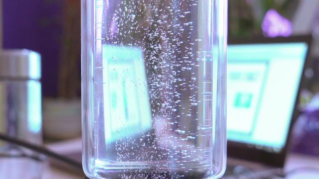 Slow motion. glass flask / glass with water. the gas bubbles slowly rise up. the work of a molecular hydrogen generator. shooting in the backlight. healthy water.
