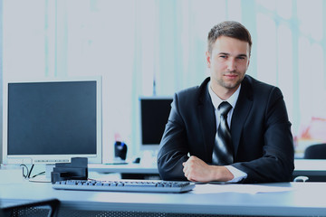 young businessman working in office, sitting at desk.