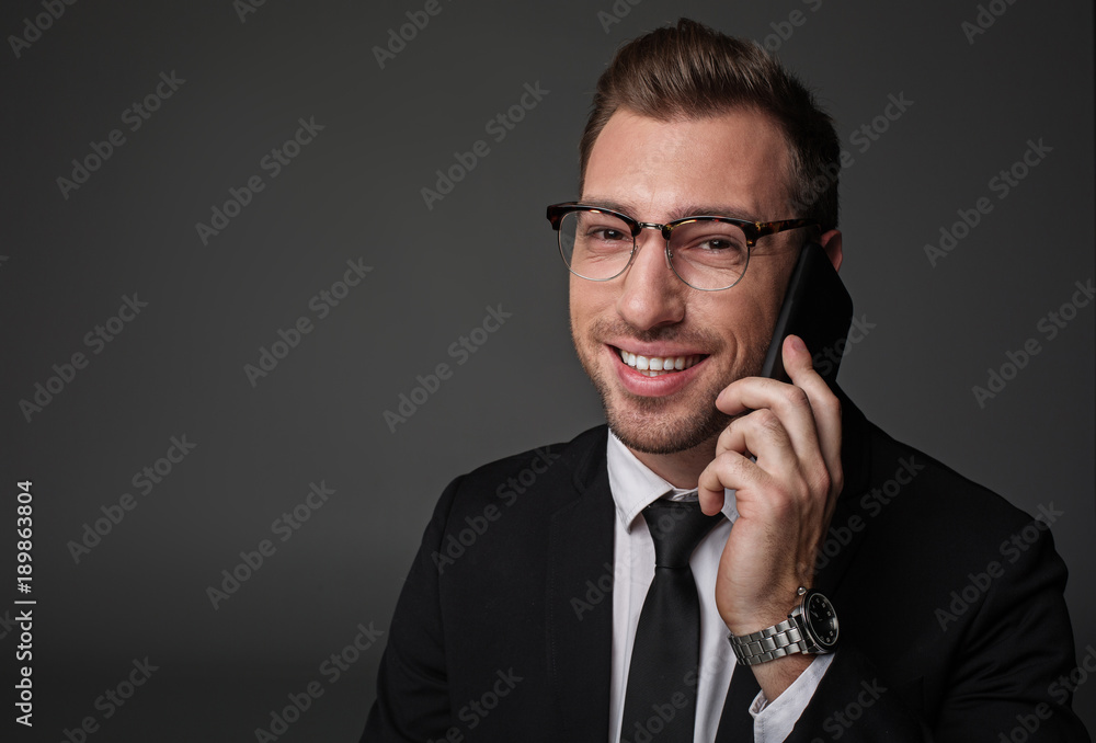 Poster portrait of bearded businessman expressing cheerfulness while speaking by phone. he looking at camer