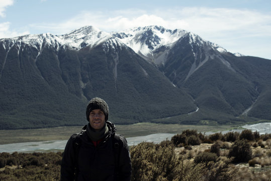 Hombre joven posando frente a un paisaje de montaña en la naturaleza