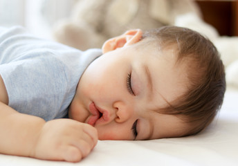 Cute little baby sleeping on stomach with funny open mouth. Daytime sleeping. Close-up.