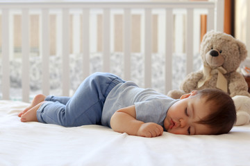 Funny baby sleeping on his stomach on bed at home. Child daytime bottom up sleeping position - obrazy, fototapety, plakaty