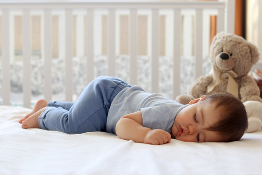 Funny baby sleeping on his stomach on bed at home. Child daytime bottom up sleeping position