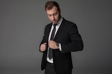 Portrait of calm businessman looking at watch. It locating on arm. Time and career concept. Isolated - obrazy, fototapety, plakaty