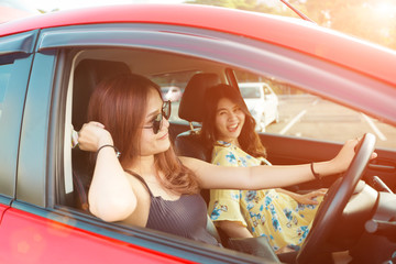 Enjoying woman and friend  driving in red car summer vacation, holidays, travel, road trip and people concept .